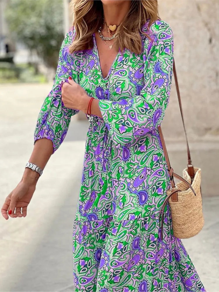 Woman wearing a colorful patterned dress with a straw bag outdoors.