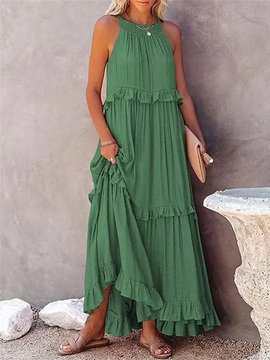 Woman wearing a green dress with ruffled layers against a stone wall.