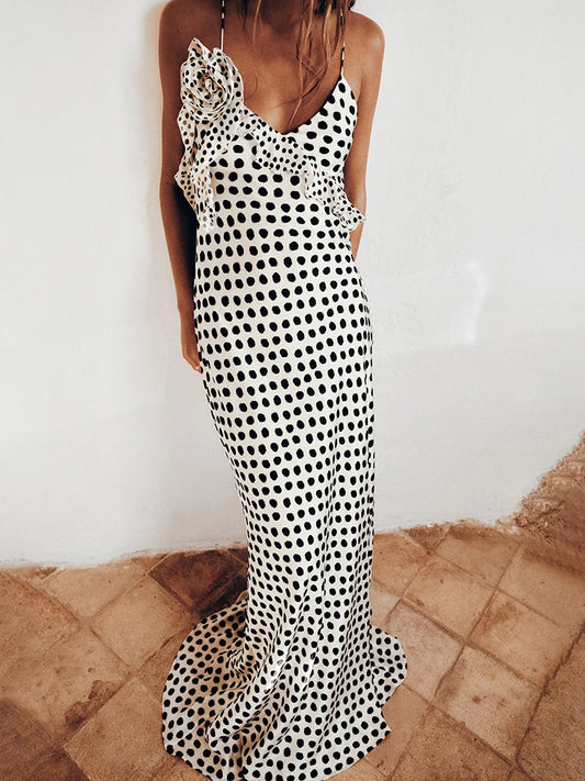 Woman wearing a black and white polka dot dress on a stone floor.