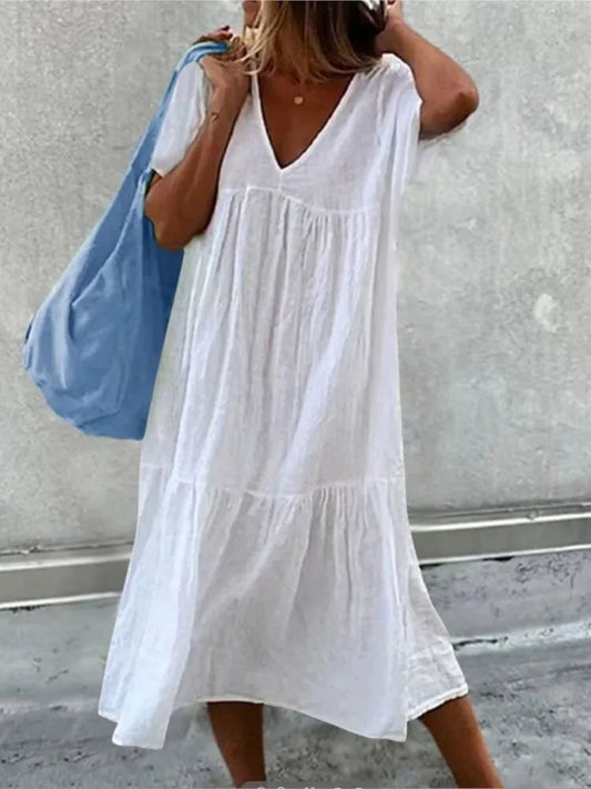 Woman wearing a white dress holding a blue bag against a gray background