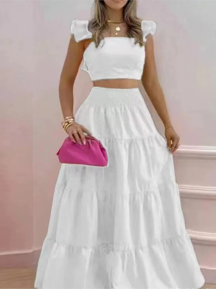 Woman wearing a white two-piece outfit with a pink clutch against a pink background