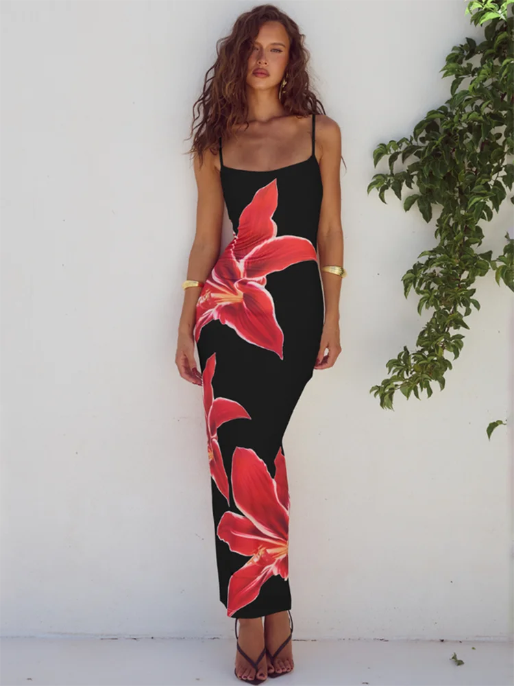 Woman wearing a black dress with red floral patterns against a white wall.