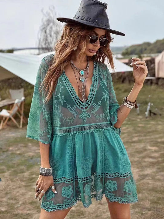 Woman wearing a teal lace dress and black hat in an outdoor setting