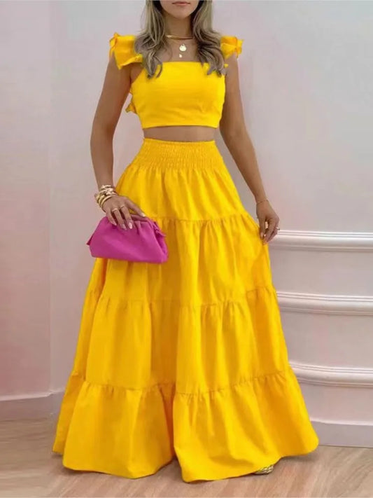 Woman wearing a yellow two-piece outfit with a pink clutch against a light background