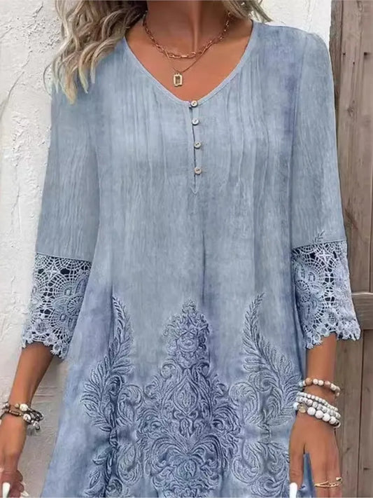 Woman wearing a blue embroidered dress with lace sleeves against a wooden background