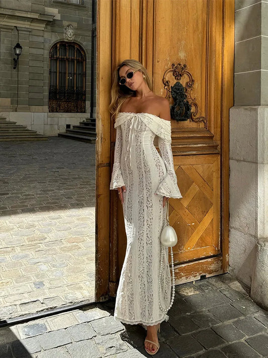 Woman in a white off-shoulder dress standing in front of a large wooden door.