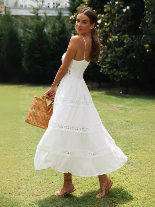 Woman in a white dress holding a straw bag on a grassy area